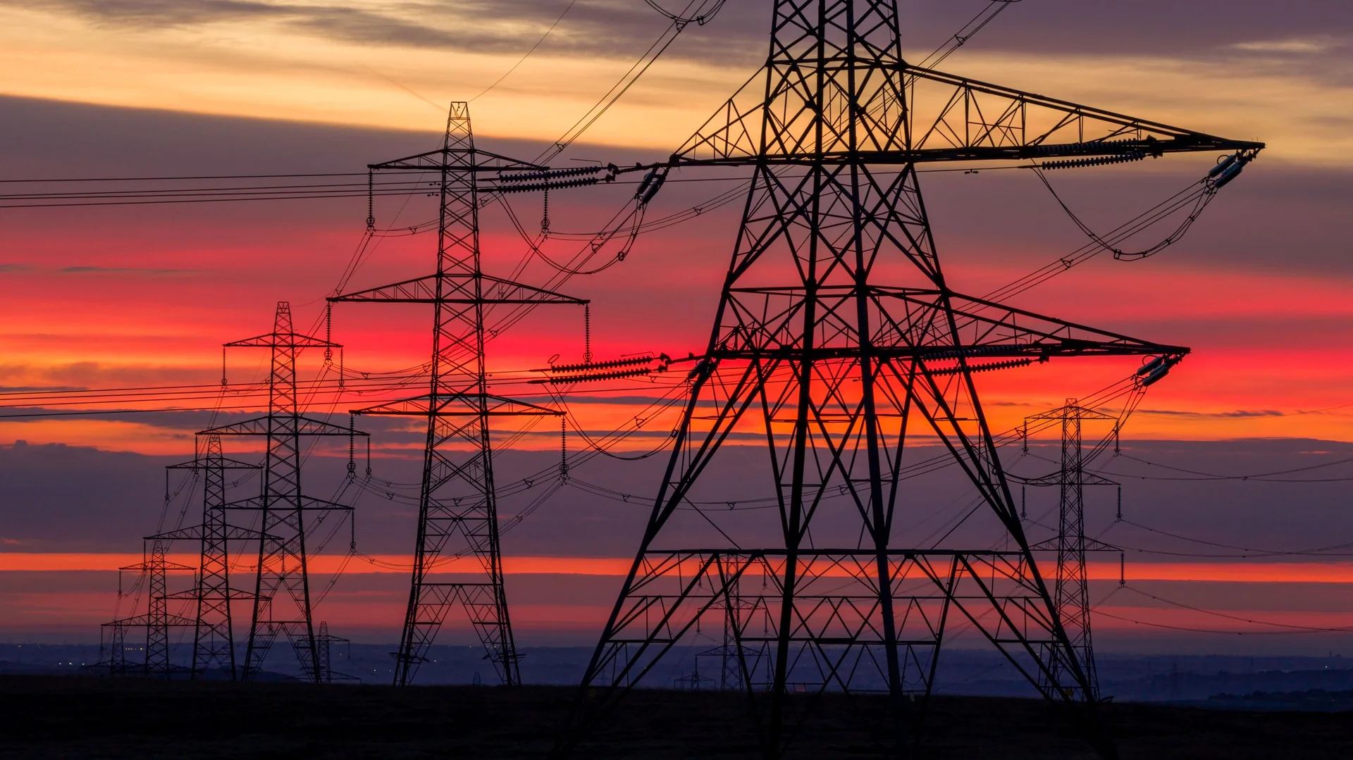Electricity pylons and transmission lines at sunset